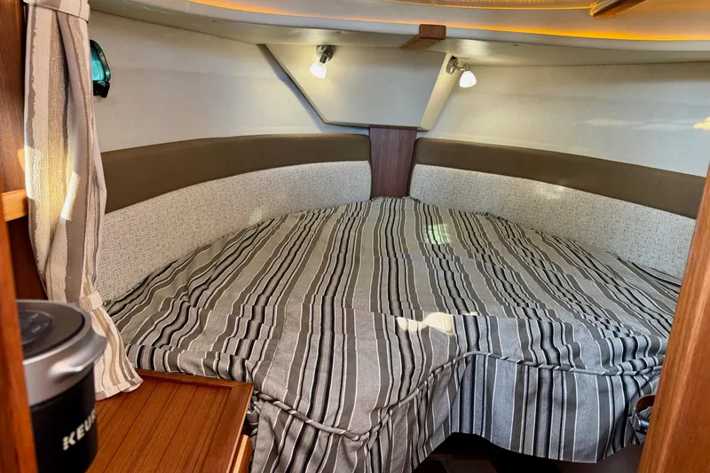 Noodles Yacht Photos Pics 2024 Ranger Tugs R-27 cabin interior with striped bedding and cozy lighting.