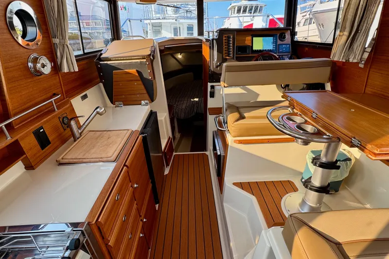 Noodles Yacht Photos Pics 2024 Ranger Tugs R-27 interior with wood finish, kitchenette, and seating area.