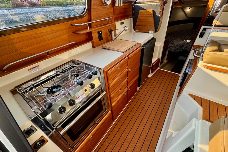 Noodles Yacht Photos Pics 2024 Ranger Tugs R-27 interior with modern kitchen, wood cabinetry, and compact design.