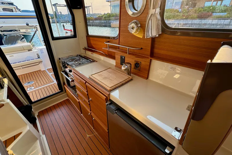 Noodles Yacht Photos Pics 2024 Ranger Tugs R-27 interior kitchen with wood cabinetry and modern appliances.