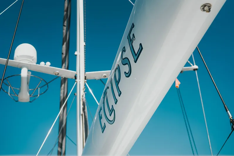 Eclipse Yacht Photos Pics Sailboat mast with "Eclipse" text, Alloy Yachts Dubois Design, 1991 model, against clear blue sky.