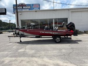 2024 Tracker Pro Team 190 TX boat in a parking lot, red color, side view.