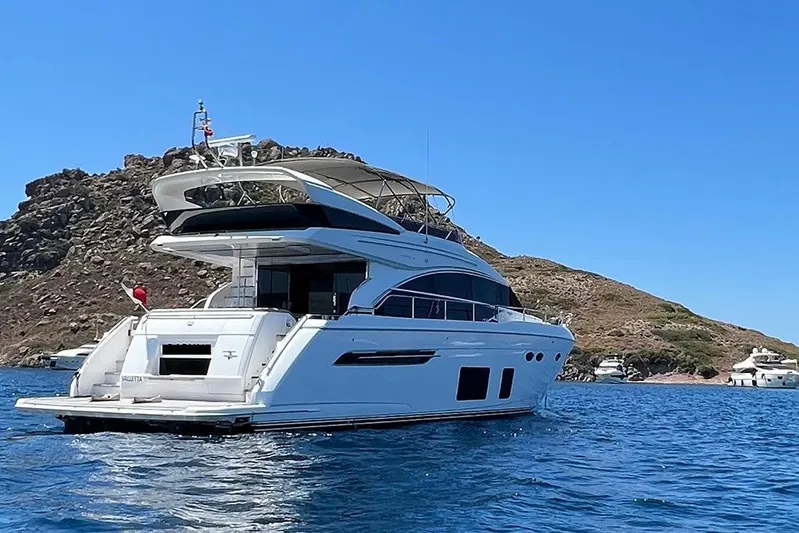Daphne Yacht Photos Pics Luxurious 2018 Princess 68 yacht cruising near rocky coastline under clear blue sky.