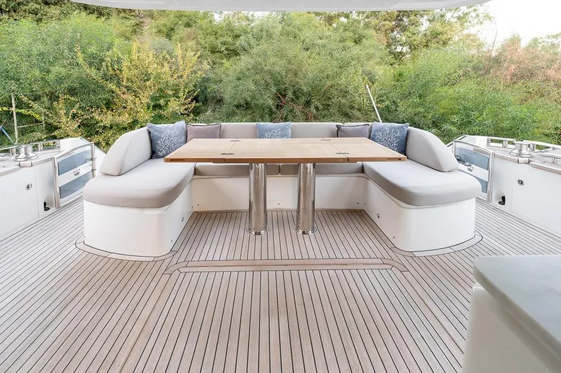 Daphne Yacht Photos Pics Luxurious 2018 Princess 68 yacht deck with elegant seating and wooden table, surrounded by greenery.