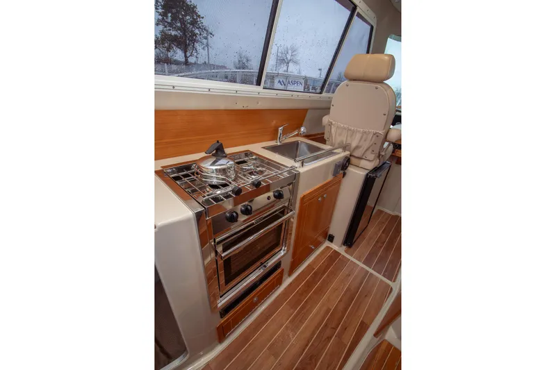  Yacht Photos Pics 2019 Aspen C107 boat interior with kitchen, stove, sink, and captain's chair.