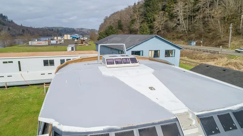 Mai Cat Yacht Photos Pics 2025 Catamaran Bloomfield 86 Motorsailor with solar panels, docked near buildings and trees.