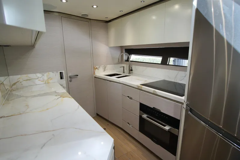  Yacht Photos Pics Modern kitchen interior on 2024 Uniesse HTC5P yacht with marble countertops and stainless steel appliances.