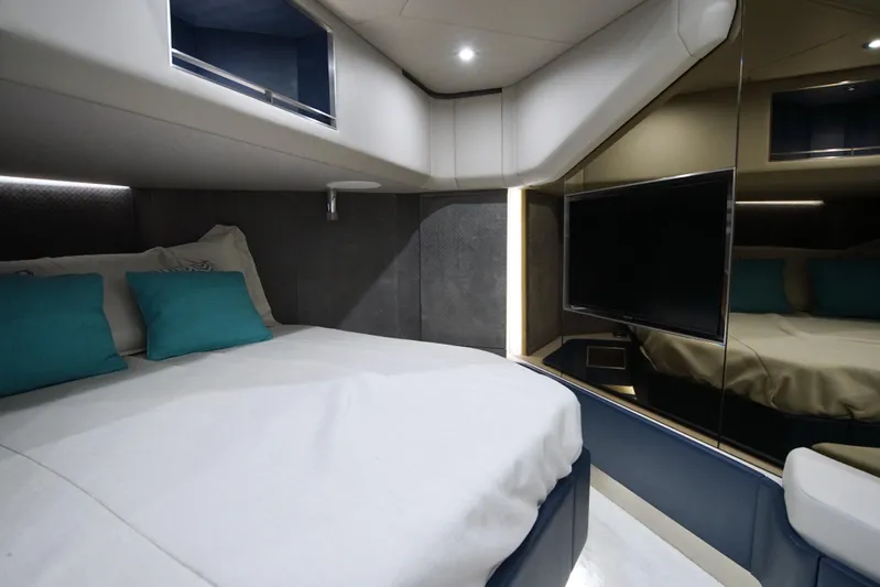  Yacht Photos Pics Luxurious 2024 Uniesse HTC5P yacht cabin with modern bedding and wall-mounted TV.
