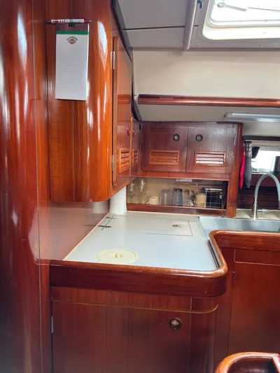 Southern Sky Yacht Photos Pics 1991 Beneteau Oceanis 510 yacht interior with wooden cabinetry and compact kitchen area.