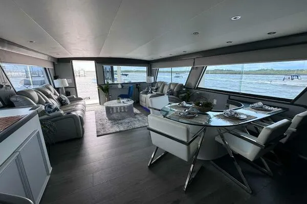 Still Pure Joy Yacht Photos Pics Luxurious interior of a 1987 Hatteras 63 yacht with modern furnishings and panoramic windows.