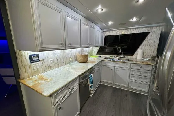 Still Pure Joy Yacht Photos Pics Modern kitchen interior on a 1987 Hatteras 63 yacht, featuring sleek cabinetry and ambient lighting.