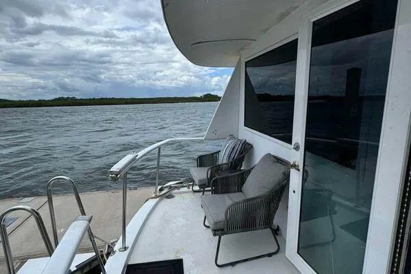 Still Pure Joy Yacht Photos Pics 1987 Hatteras 63 yacht deck with chairs overlooking serene waters.