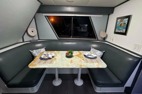 Still Pure Joy Yacht Photos Pics Dining area in a 1987 Hatteras 63 yacht with a cozy booth and elegant table setting.
