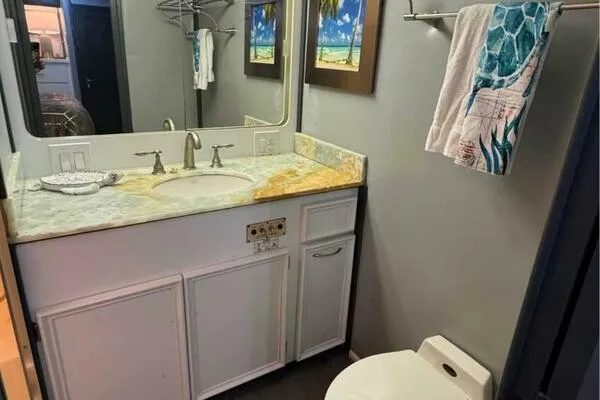 Still Pure Joy Yacht Photos Pics Bathroom interior of 1987 Hatteras 63 yacht with sink, mirror, and tropical decor.