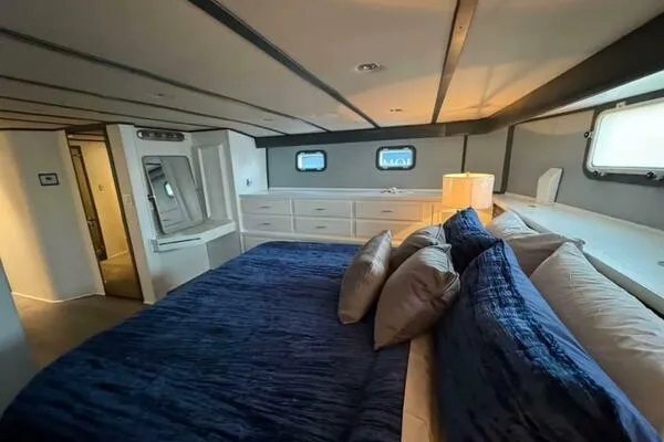 Still Pure Joy Yacht Photos Pics Luxurious bedroom interior of a 1987 Hatteras 63 yacht with blue bedding and ample storage.