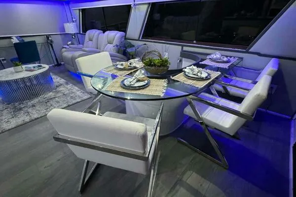 Still Pure Joy Yacht Photos Pics Luxurious interior of a 1987 Hatteras 63 yacht with modern dining area and ambient lighting.