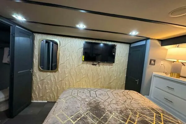 Still Pure Joy Yacht Photos Pics Luxurious bedroom interior of 1987 Hatteras 63 yacht with modern decor and wall-mounted TV.