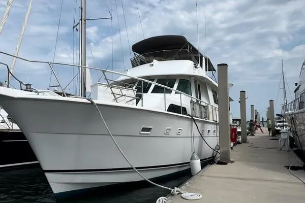 Still Pure Joy Yacht Photos Pics 1987 Hatteras 63 yacht docked at marina under cloudy sky.