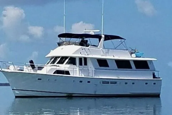 Still Pure Joy Yacht Photos Pics 1987 Hatteras 63 yacht on calm water under a clear sky.