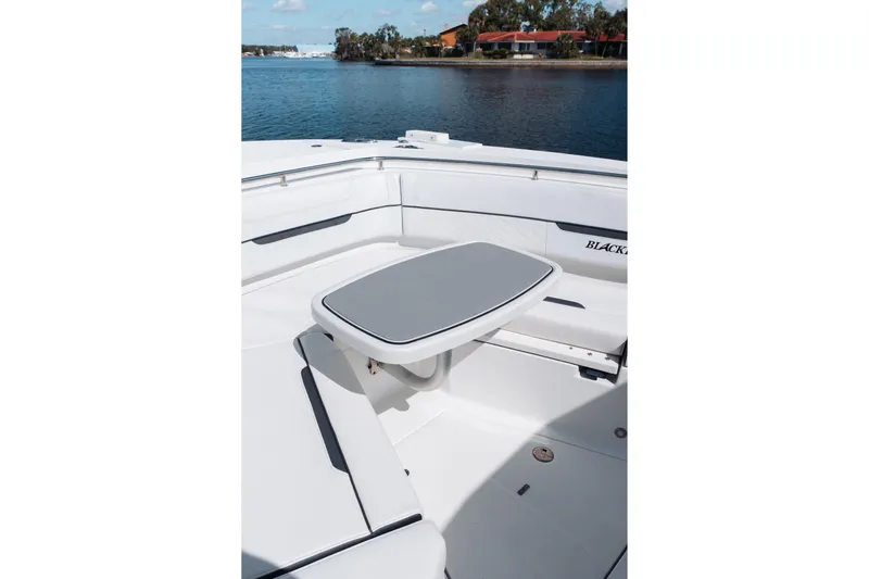 Lickety-split Yacht Photos Pics 2021 Blackfin 332 CC boat interior with seating and table, near calm water.