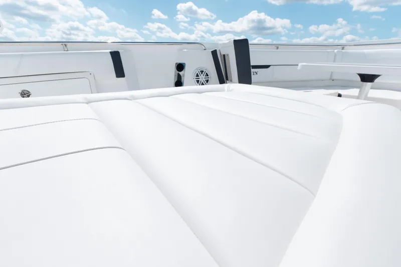 Lickety-split Yacht Photos Pics 2021 Blackfin 332 CC boat interior with white cushioned seating under a blue sky.