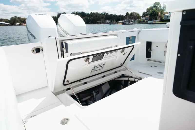 Lickety-split Yacht Photos Pics 2021 Blackfin 332 CC boat with open storage compartment, twin Mercury engines, and scenic water backdrop.