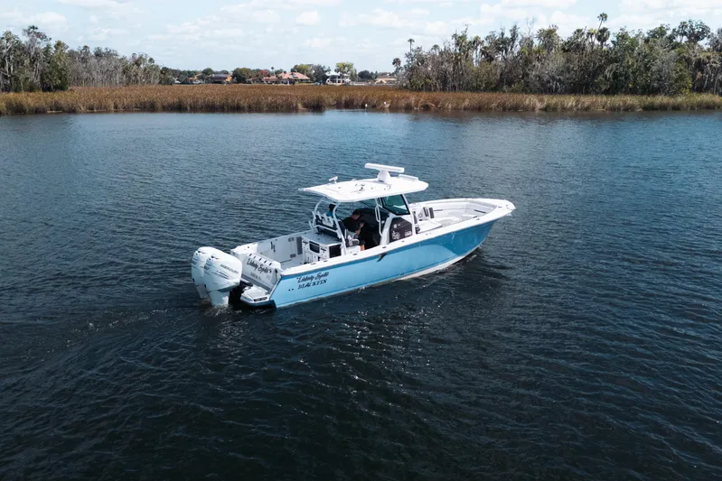 Lickety-split Yacht Photos Pics 2021 Blackfin 332 CC boat cruising on a calm lake with scenic shoreline.