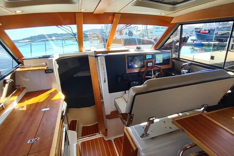 Wyvern Yacht Photos Pics 2020 Cutwater C-32 Coupe interior with helm, navigation screens, and wooden accents.