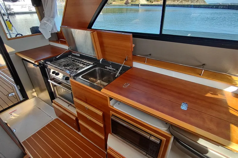 Wyvern Yacht Photos Pics 2020 Cutwater C-32 Coupe kitchen with stove, sink, and wooden cabinetry.