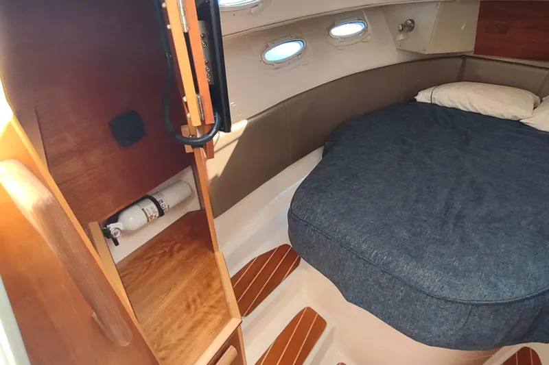 Wyvern Yacht Photos Pics 2020 Cutwater C-32 Coupe cabin interior with bed, wooden storage, and portholes.