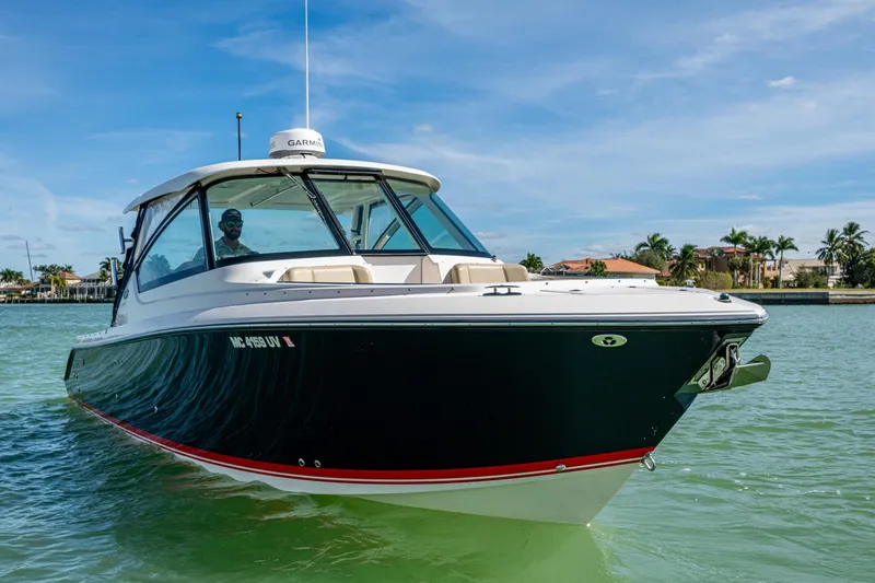  Yacht Photos Pics 2017 Pursuit DC 295 Dual Console boat cruising on clear waters, with a scenic coastal backdrop.