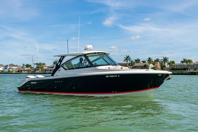  Yacht Photos Pics 2017 Pursuit DC 295 Dual Console boat on calm water, with palm trees in the background.