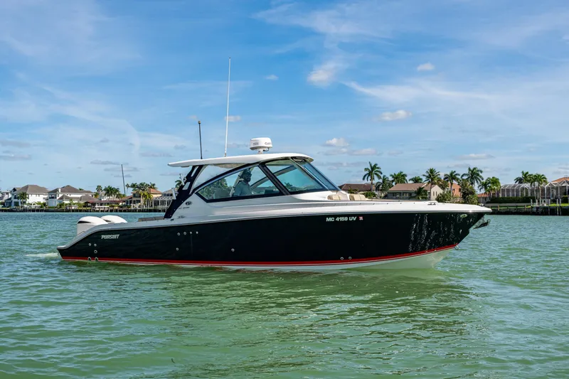  Yacht Photos Pics 2017 Pursuit DC 295 Dual Console boat on calm water, with palm trees in the background.