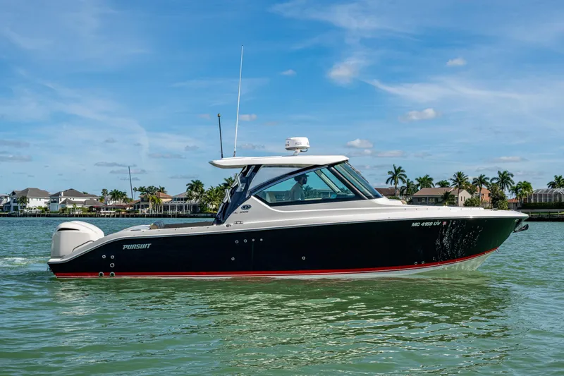  Yacht Photos Pics 2017 Pursuit DC 295 Dual Console boat on calm water, with a scenic coastal backdrop.