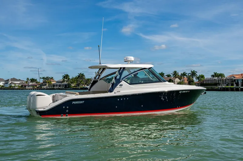  Yacht Photos Pics 2017 Pursuit DC 295 Dual Console boat cruising on a sunny day near waterfront homes.