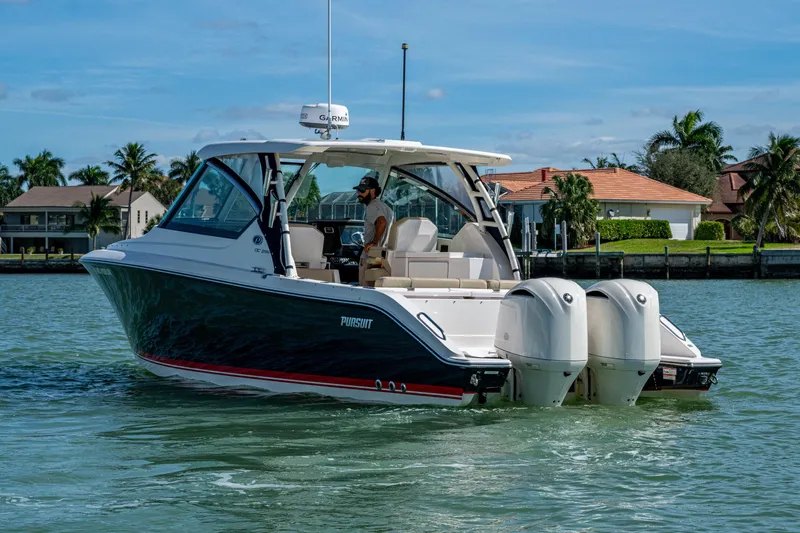  Yacht Photos Pics 2017 Pursuit DC 295 Dual Console boat cruising on a sunny day near waterfront homes.