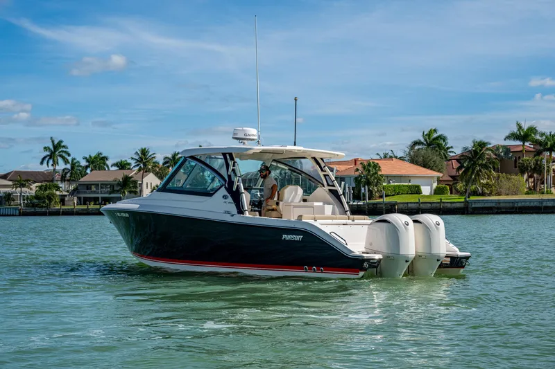  Yacht Photos Pics 2017 Pursuit DC 295 Dual Console boat cruising on a sunny day near waterfront homes.