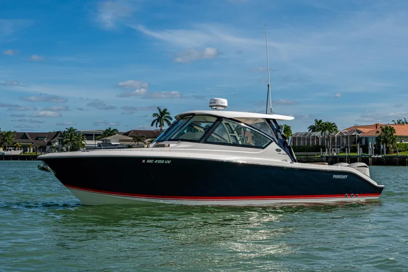  Yacht Photos Pics 2017 Pursuit DC 295 Dual Console boat on calm water, with houses in the background.