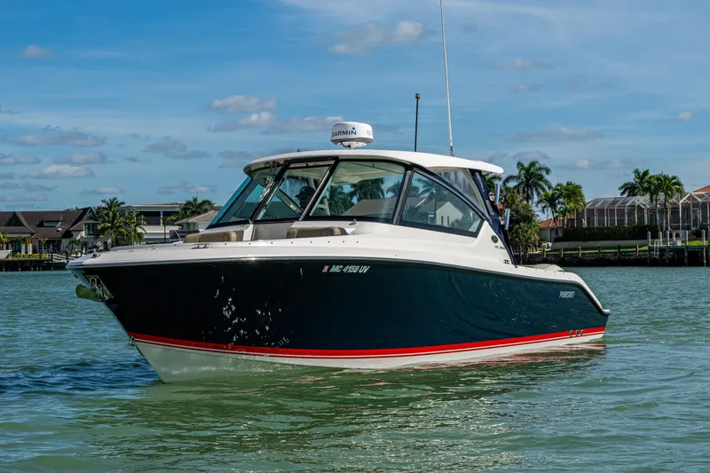  Yacht Photos Pics 2017 Pursuit DC 295 Dual Console boat on calm water, with coastal homes in the background.
