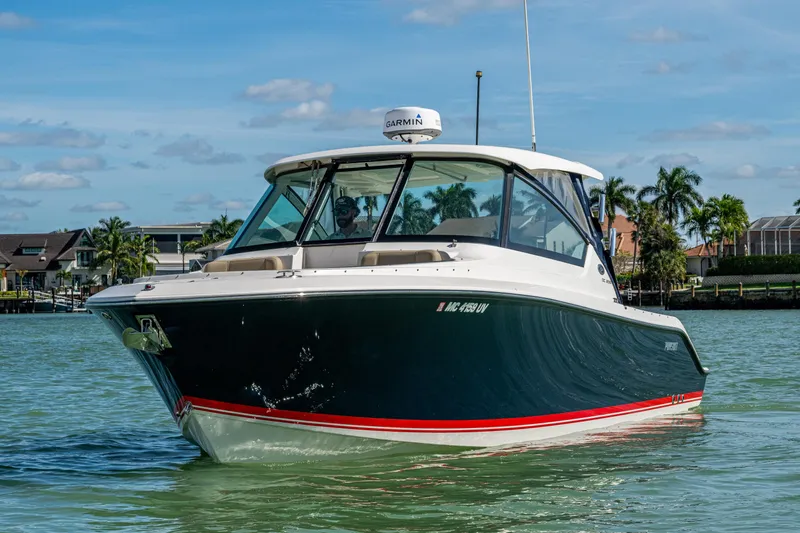  Yacht Photos Pics 2017 Pursuit DC 295 Dual Console boat cruising on a sunny day near palm trees.