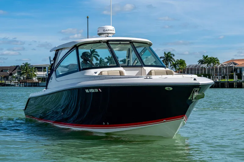  Yacht Photos Pics 2017 Pursuit DC 295 Dual Console boat cruising on a sunny day near waterfront homes.