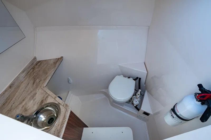 Yacht Photos Pics 2017 Pursuit DC 295 Dual Console boat bathroom with sink, toilet, and fire extinguisher.