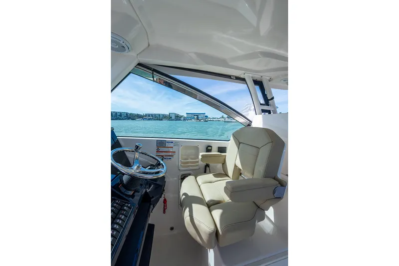  Yacht Photos Pics 2017 Pursuit DC 295 Dual Console interior with steering wheel and beige captain's chair.
