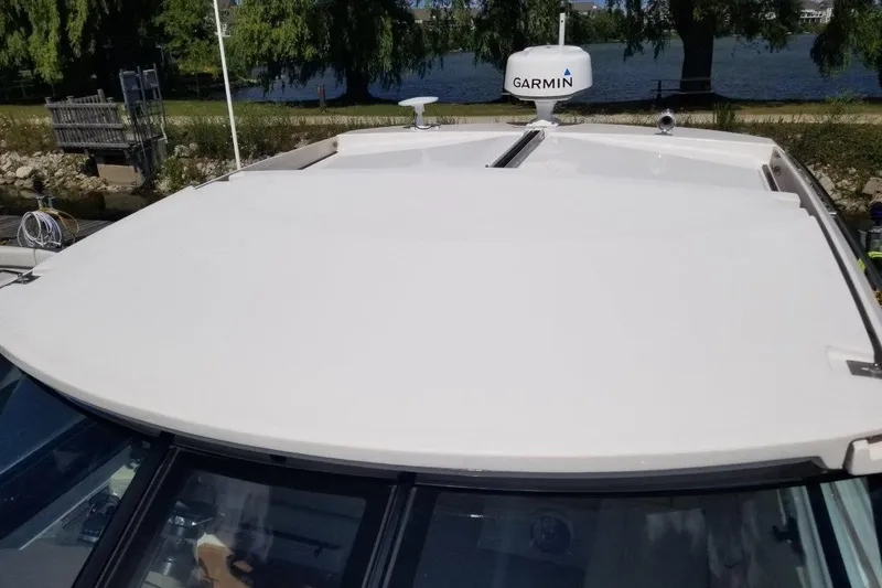 Ships N Giggles Yacht Photos Pics 2018 Regal 35 Sport Coupe boat roof with Garmin radar, docked by a scenic river.