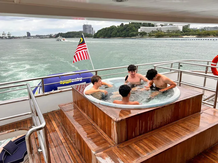  Yacht Photos Pics Four people relaxing in a hot tub on a 2012 Superyacht 128, with a scenic ocean view.