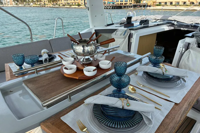  Yacht Photos Pics Elegant dining setup on 2020 Beneteau Oceanis 41.1 yacht, featuring blue glassware and fondue set.
