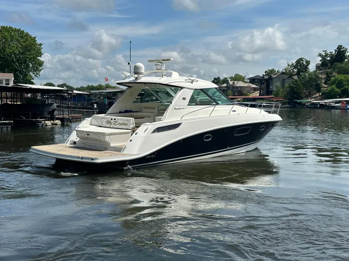  Yacht Photos Pics 2010 Sea Ray 450 Sundancer yacht on a calm lake under a partly cloudy sky.
