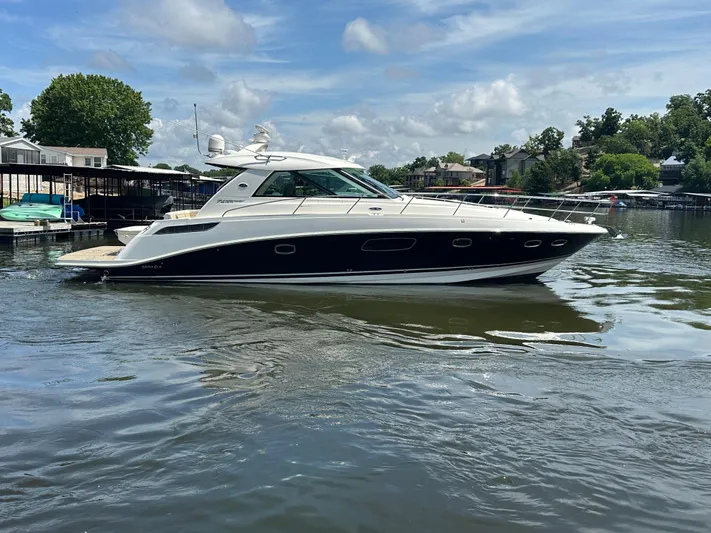  Yacht Photos Pics 2010 Sea Ray 450 Sundancer yacht on a calm lake under a partly cloudy sky.