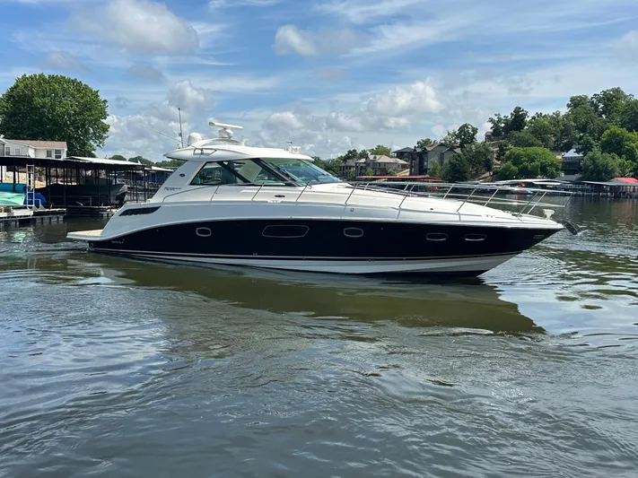  Yacht Photos Pics 2010 Sea Ray 450 Sundancer yacht on calm water, surrounded by trees and docks.