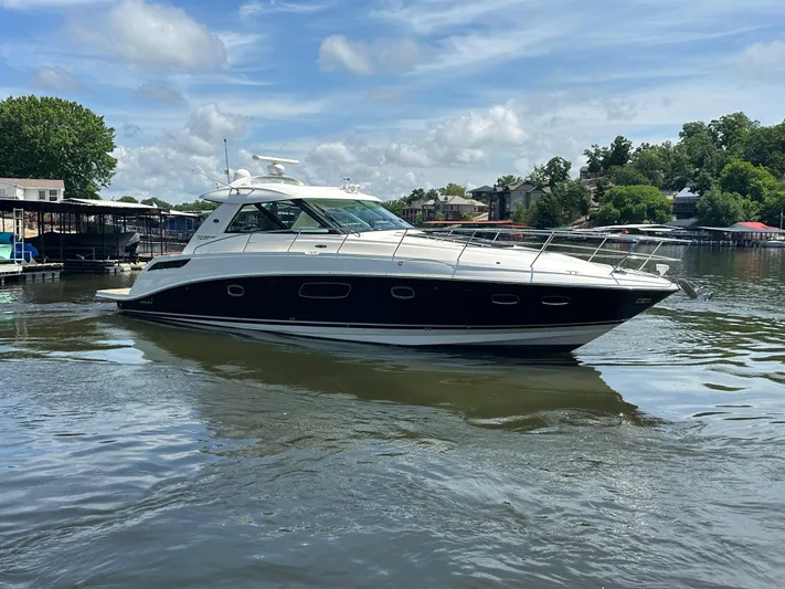  Yacht Photos Pics 2010 Sea Ray 450 Sundancer yacht on a calm lake under a partly cloudy sky.